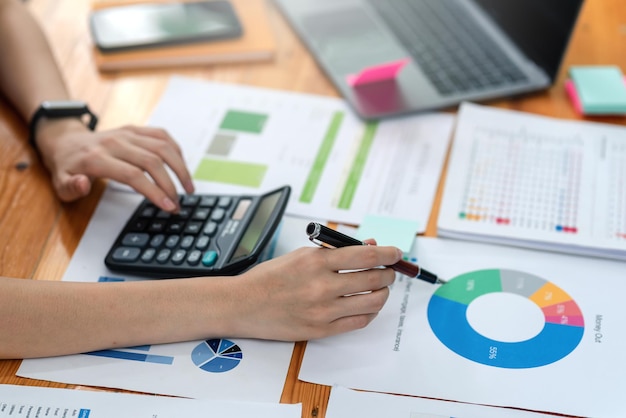 Zakenvrouw hand bezig met het analyseren van statistische boekhoudkundige inkomsten met behulp van een grafiek rekenmachine op kantoor.