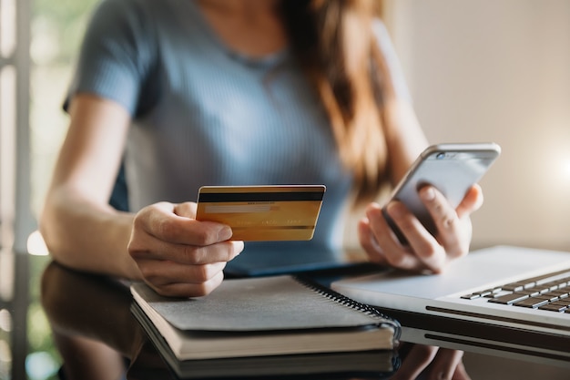 Zakenvrouw hand met behulp van slimme telefoon, tablet betalingen en creditcard online winkelen, omni channel, digitale tablet docking toetsenbordcomputer op kantoor in zonlicht