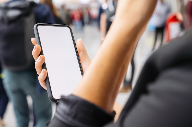 Zakenvrouw hand met zwarte mobiele telefoon met wit scherm op een beurs, copyspace voor uw individuele tekst.