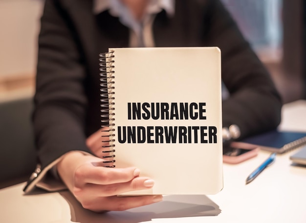 Zakenvrouw houdt een notitieboekje vast met de tekst INSURANCE UNDERWRITER