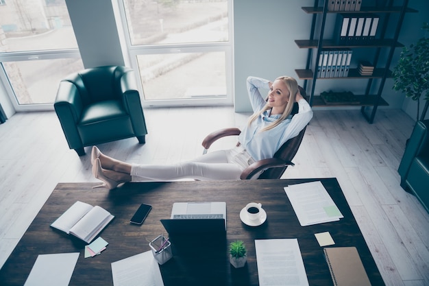 Zakenvrouw houdt handen achter hoofd benen bureau