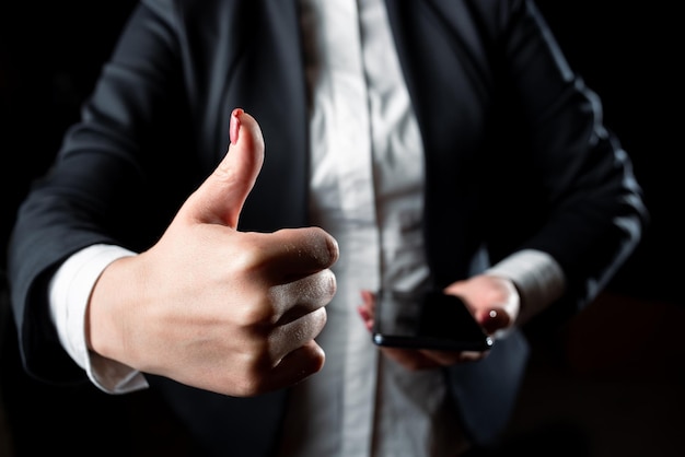 Zakenvrouw houdt mobiele telefoon vast en toont ok teken Vrouw met telefoon in één hand en duimen omhoog met andere dame met tablet presenteren symbool met één vinger