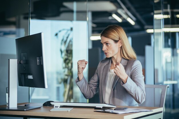 Zakenvrouw Ik kan alles doen portret van een succesvolle zakenvrouw die naar de camera kijkt en glimlacht terwijl ze in een modern kantoor werkt op een computergebaar van succes en overwinning