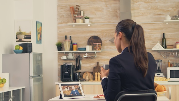 Zakenvrouw in een videogesprek met haar vader tijdens haar vader tijdens het ontbijt. Moderne online internetwebtechnologie gebruiken om via de webcam-videoconferentie-app te chatten met familieleden, familie, vrienden