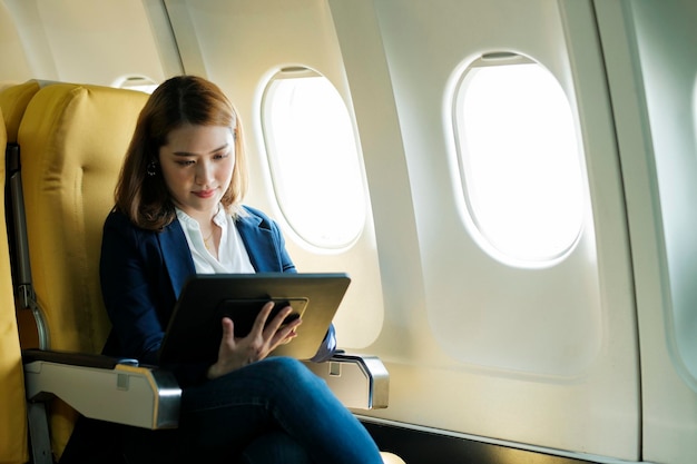 Zakenvrouw In een vliegtuig en werkt op laptop