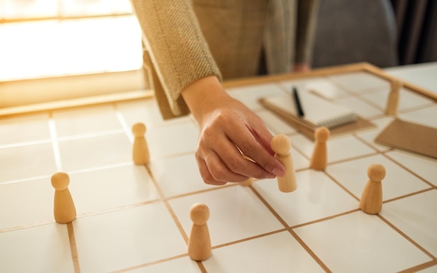 Zakenvrouw leider die houten mensen kiest uit een groep werknemers op een planbord