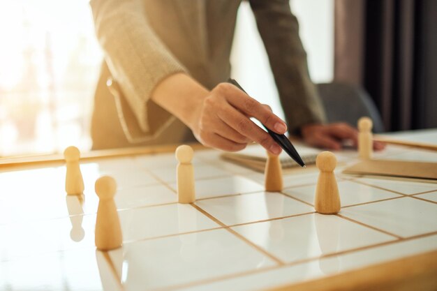 Zakenvrouw leider kiezen en wijzend op een van de houten mensen uit een groep werknemers op een planbord