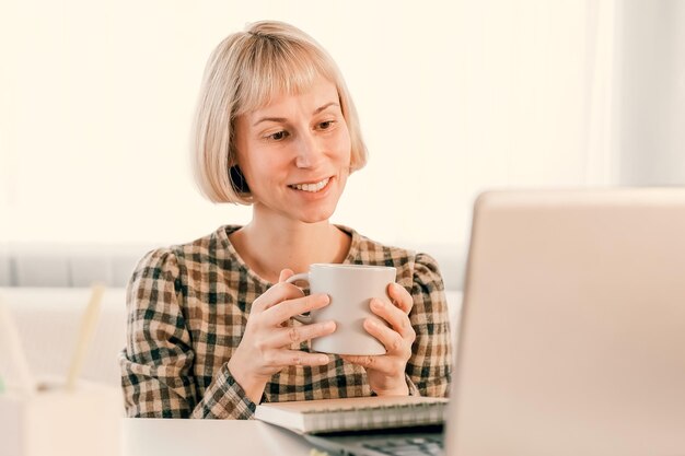 Zakenvrouw luisteren educatieve lezing op computer kijken webinar studeren op online cursussen schrijven van notities in papieren beurt e-learning concept