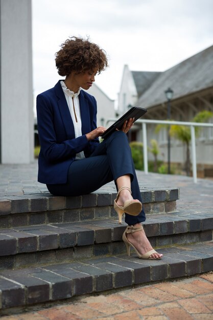 Zakenvrouw met behulp van digitale tablet in de buurt van kantoorgebouw