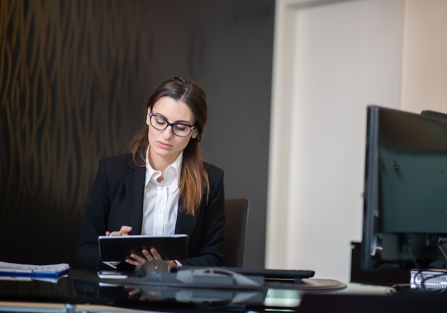 Zakenvrouw met behulp van een tablet in haar bedrijfsbureau, het concept van de onderneemstercarrière