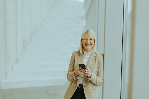 Zakenvrouw met behulp van mobiele telefoon op moderne kantoor hal