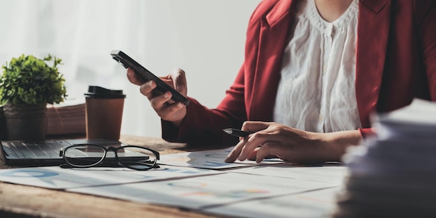 Zakenvrouw met behulp van telefoon voor wiskunde financiën op houten bureau in kantoor en zakelijke achtergrond belastingboekhouding statistieken en analytisch onderzoek conceptx9