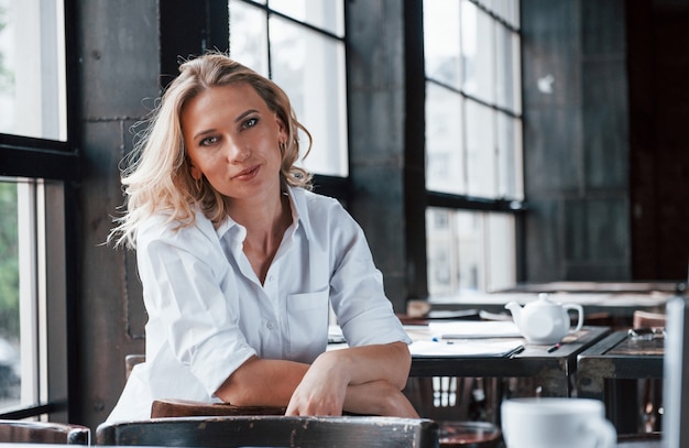 Zakenvrouw met blond krullend haar binnenshuis in café overdag.