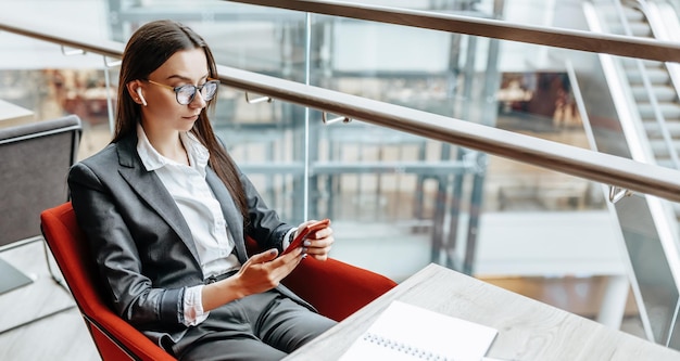 Zakenvrouw met een bril op de werkplek gebruikt de telefoon en zit aan tafel Manager op kantoor