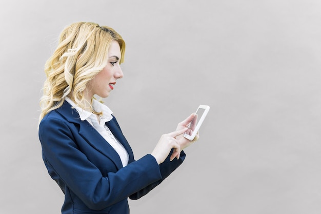zakenvrouw met een digitale tablet tegen een witte muur