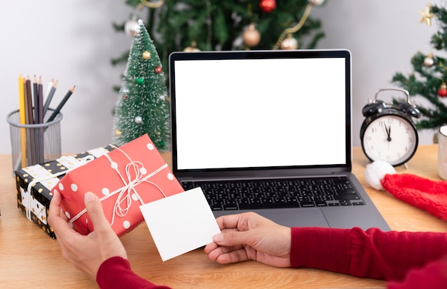 Zakenvrouw met geschenkdoos en wenskaart op kantoortafel op eerste kerstdag