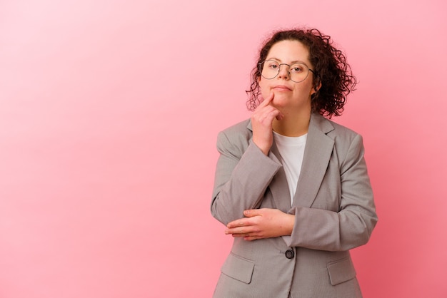 Zakenvrouw met het syndroom van Down geïsoleerd op roze muur ontspannen denken aan iets kijken naar een kopie ruimte.