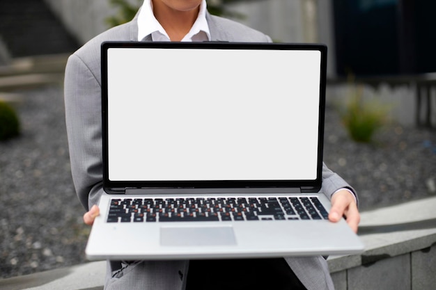 Zakenvrouw met laptopcomputer met leeg wit scherm op straatmodel