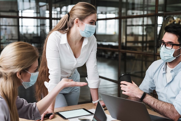 Foto zakenvrouw met medisch masker met een professionele bijeenkomst met haar collega's