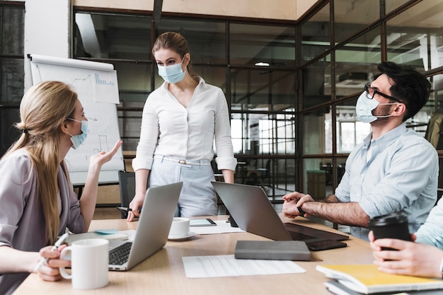 Foto zakenvrouw met medisch masker tijdens een professionele bijeenkomst