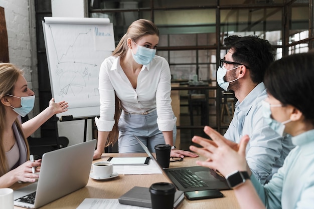 Zakenvrouw met medisch masker tijdens een professionele ontmoeting met haar collega's