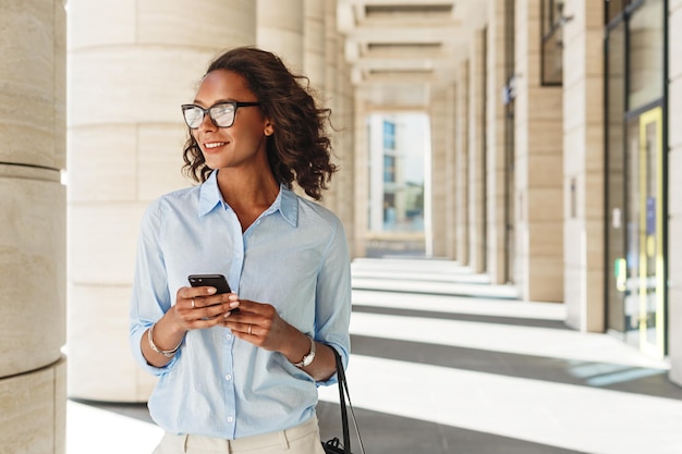 Zakenvrouw met mobiele telefoon terwijl ze in de stad staat