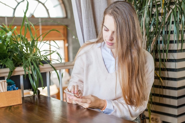 Zakenvrouw met smartphone die in een open kantoor werkt