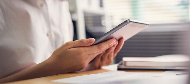 Zakenvrouw met tablet en gebruikt om online te werken op de tafel op kantoor.