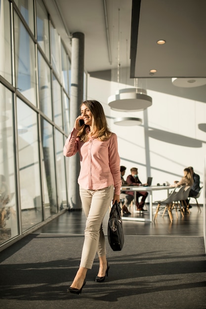 Zakenvrouw op mobiele telefoon wandelen in het kantoor