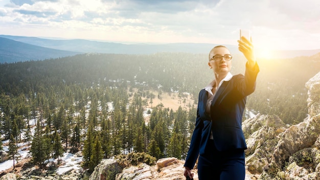 Zakenvrouw permanent tegen landschap en selfie maken. Gemengde media