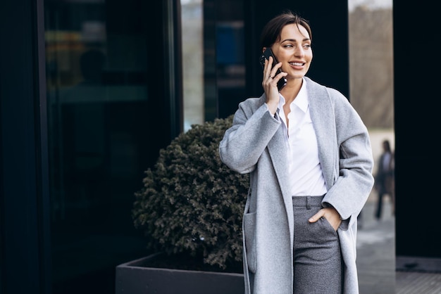 Zakenvrouw praten aan de telefoon buiten kantoorgebouw