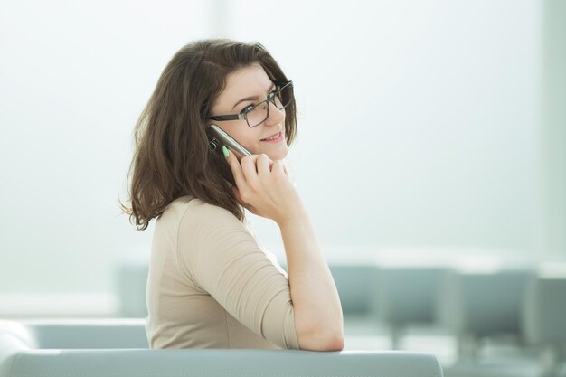 Zakenvrouw praten op een smartphone zittend in de kantoorruimte