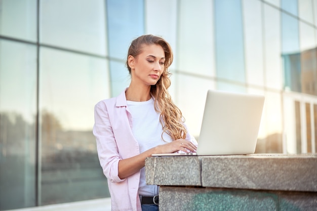 Zakenvrouw staande corporate gebouw zomerdag met behulp van laptop business persoon werkt op afstand