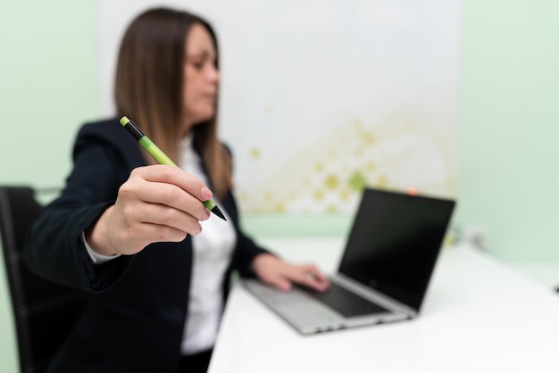 Zakenvrouw typen recente updates op Lap Top toetsenbord op Bureau en wijzen belangrijke ideeën met Pen vrouw In Office late berichten schrijven op Computer