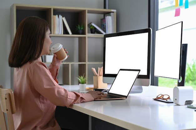 Zakenvrouw warme koffie drinken en werken met laptop in kantoorruimte