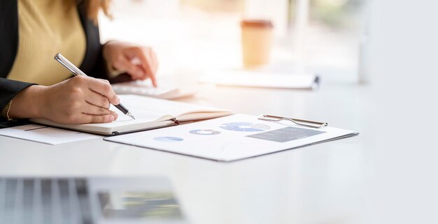 Zakenvrouw werken op kantoor met document op haar bureau planning analyseren van het financiële verslag business plan investeringen financiën analyse concept met behulp van rekenmachine en laptopcomputer