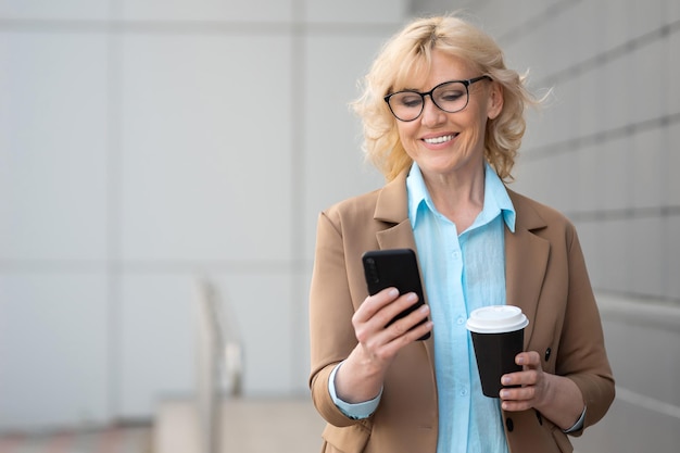 Zakenvrouw werkt aan een smartphone en drinkt een kop koffie