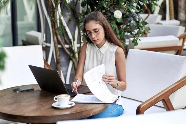 Zakenvrouw werkt met documenten aan een tafel in een café