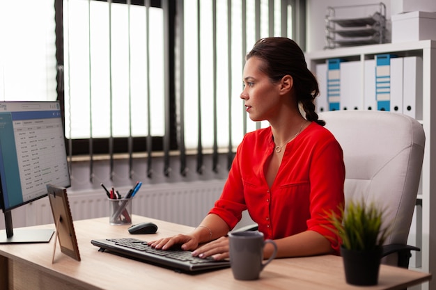 Zakenvrouw zakelijke ondernemer geconcentreerd kijken naar computerscherm op kantoor werkplek. Succesvolle zelfverzekerde vrouw in marketing zit aan de balie op de werkplek met behulp van computer.