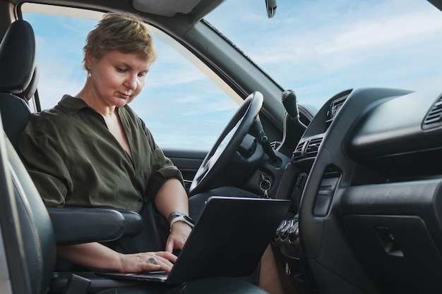 Zakenvrouw zit in de bestuurdersstoel van een auto Ernstige vrouw van middelbare leeftijd