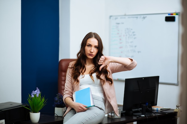 Zakenvrouw zitten aan een bureau met duim naar beneden