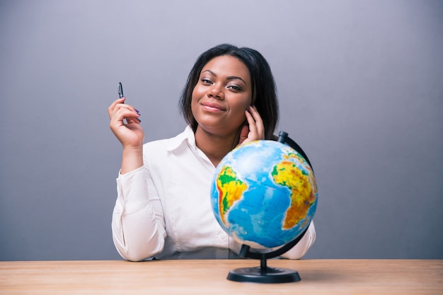 Zakenvrouw zittend aan tafel met pen en globe