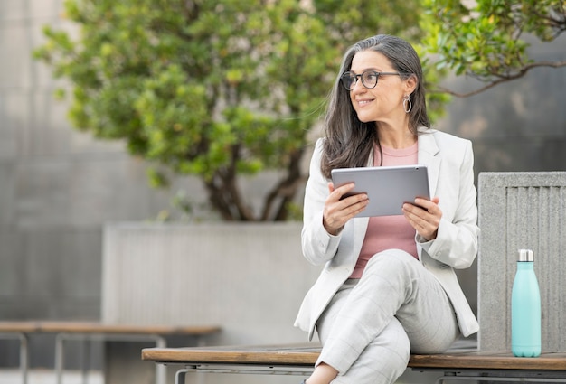 Zakenvrouw zittend op straat met tablet