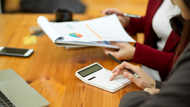 Zakenvrouwen lezen financiële documenten die werken en communiceren terwijl ze samen aan een bureau zitten