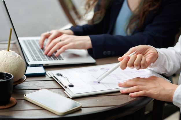 Zakenvrouwen zitten aan een tablet in een openluchtcafé en werken met financiële verslagen