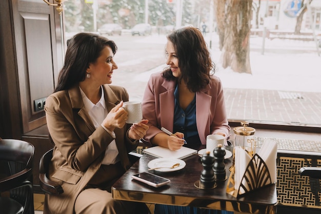 Zakenvrouwen zitten in een café, drinken koffie en hebben een zakelijk gesprek, bespreken zaken en hebben plezier