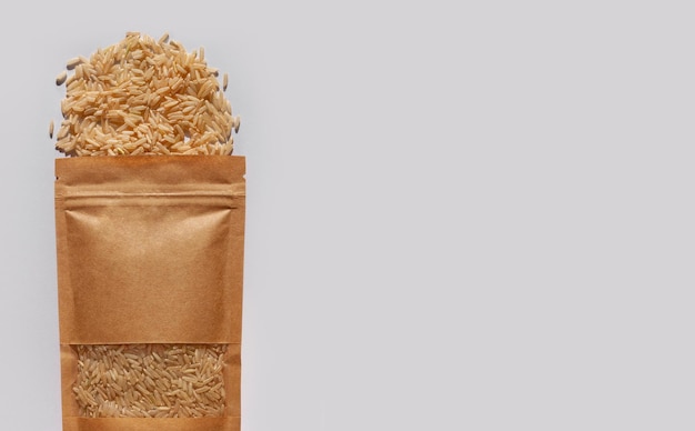 Zakje van kraftpapier met volkoren bruine rijst bovenaanzicht met harde schaduw witte achtergrond Gezonde voeding granen