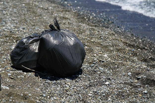 Zakken met verzameld afval van het strand voor recycling om het strand te reinigen van vervuiling