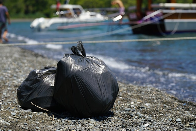 Zakken met verzameld afval van het strand voor recycling om het strand te reinigen van vervuiling