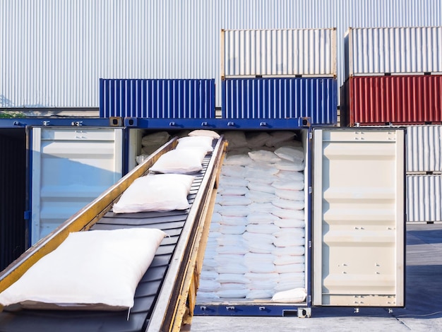 Zakken op transportband tegen vrachtcontainers